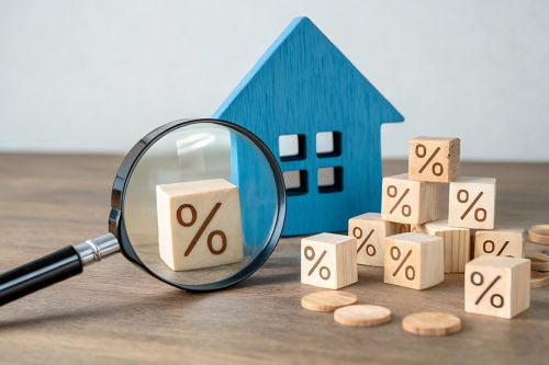 Foto: Lupe, Holzhaus und Würfel mit Prozentzeichen